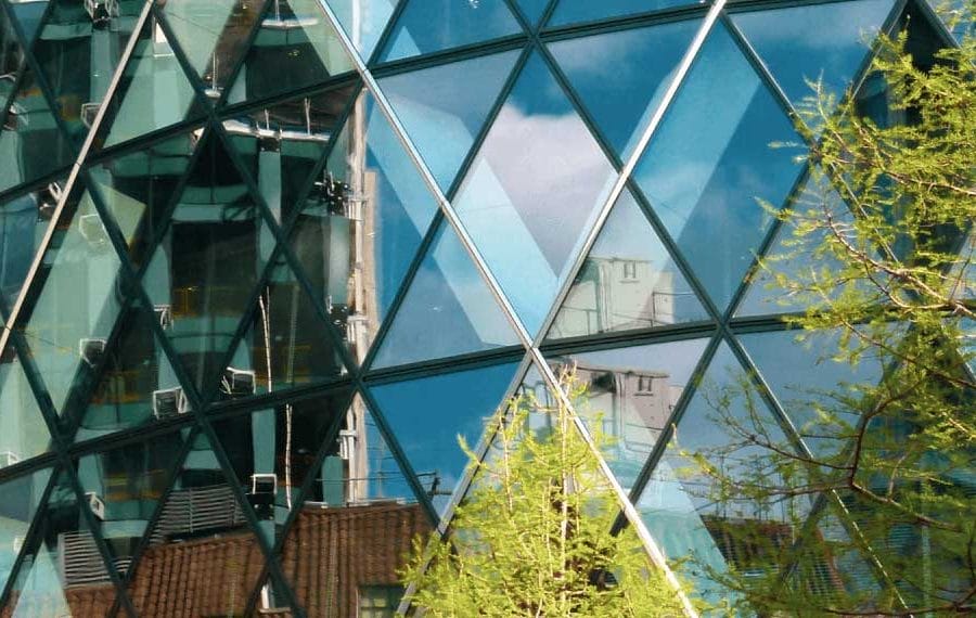 Gherkin building found in the middle of London’s financial headquarters. Mainly made of glass and steel. Tree covers right-hand side of image