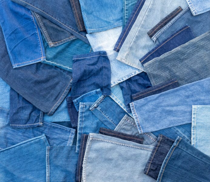Different shades of blue denim jeans, many of which are left pieces over from sewing repairs.