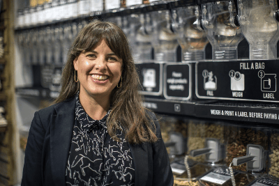 Proud refill shop owner in her sustainable store after receiving circular business advice and support to help her business grow, London