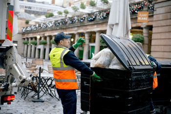 London waste recovery crew emptying large commercial bins
