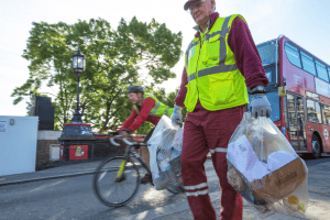 Veolia crew member carrying two clear sacks of commercial recycling waste