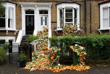 TRiFOCAL food waste campaign: Lots of fruit and vegetables are tumbling down the steps of a Victorian terraced house, out of its windows into the front garden and street, to show how we can reduce food waste to tackle the climate emergency. Photo credit: Jonathan Hordle/PA Wire